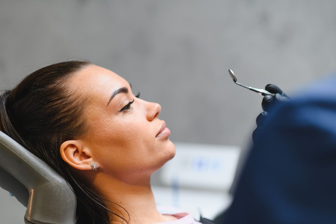 A routine exam is often where sleep concerns first come up Patient reclined in the dental chair as her dentist holds an oral mirror for an exam