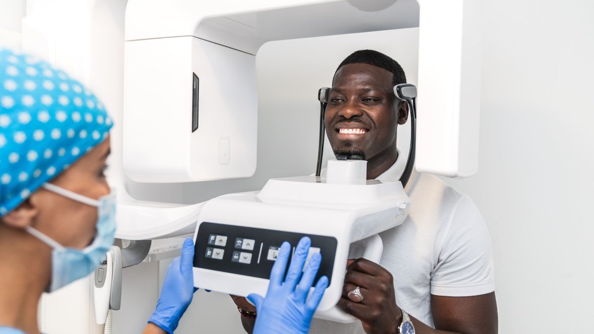 Patient positioned in a panoramic x-ray machine while the assistant sets the exposure