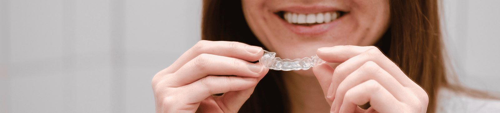 Patient holding a clear Invisalign aligner tray during an orthodontic consultation in Orlando