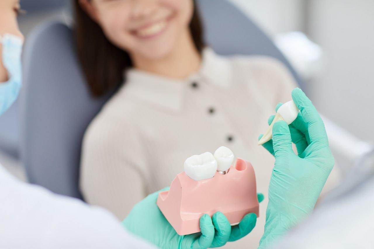 Dentist showing a patient a tooth model with a crown